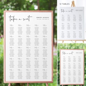 May include: A wedding seating chart with a white background and black text. The chart is titled "Take a Seat" and lists 25 tables with guest names. The chart is framed in a light brown frame and is displayed on a wooden easel.