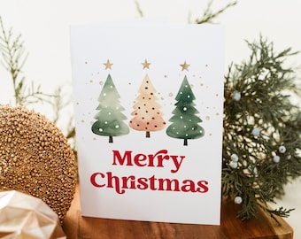 May include: A white card with a watercolour illustration of three Christmas trees with gold stars and gold glitter. The text "Merry Christmas" is written in red letters.