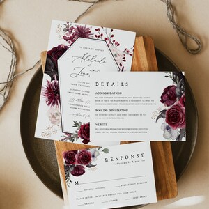 Pu&ograve; includere: Un invito di nozze floreale color borgogna e bianco con un bordo dorato. L'invito presenta il testo "Til Death Do Us Part" e i nomi "Adelaide e Jonah". L'invito include anche i dettagli del matrimonio, come la data, l'ora e il luogo. L'invito &egrave; posto su una superficie di legno.