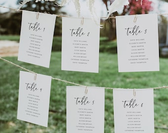 Può includere: Sei carte bianche con testo nero appese a una corda. Ogni carta ha un numero di tavolo e un elenco di nomi. I numeri dei tavoli sono 1, 2, 3, 4, 5 e 6.