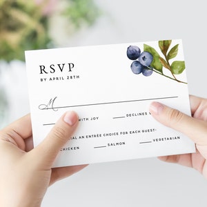 May include: RSVP card with a watercolor blueberry design. The card has a line for the guest's name, a checkbox for "with joy" and a checkbox for "declines". It also includes a section for the guest to choose their entree: chicken, salmon, or vegetarian.