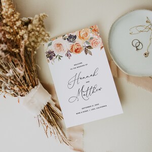 May include: Wedding invitation with a floral design in shades of peach, orange, and pink. The text reads "Welcome to the wedding of Hannah and Matthew, September 21, 20XX, Wine & Roses, Lodi, California."