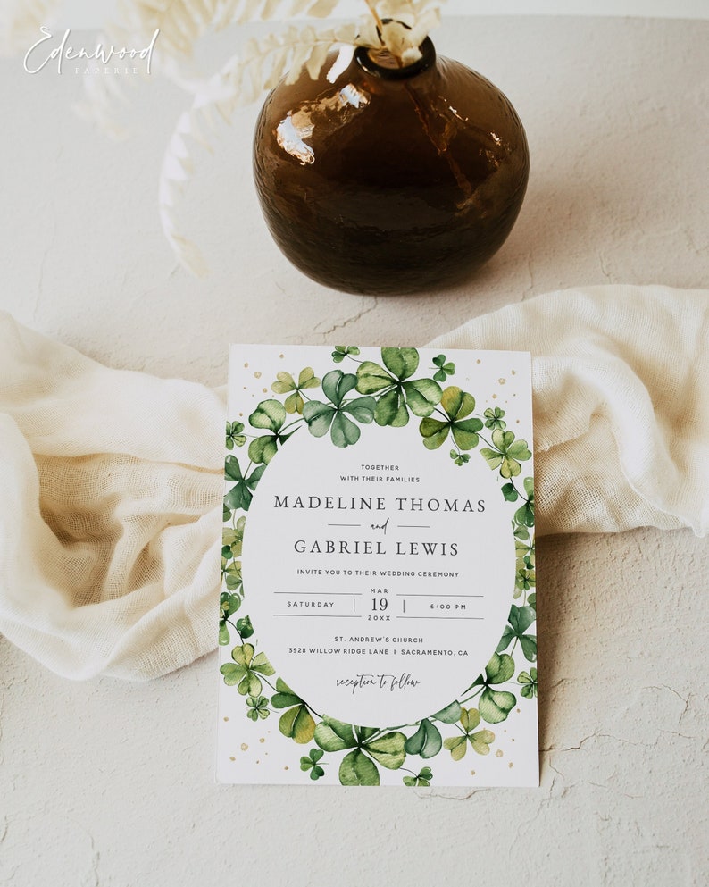 May include: A wedding invitation with a watercolor illustration of green shamrocks in a circle around the text "Madeline Thomas and Gabriel Lewis". The invitation includes the date, time, and location of the wedding ceremony. The text "reception to follow" is at the bottom of the invitation.