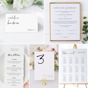 May include: Wedding seating chart with the text "take a seat" in black calligraphy. The chart lists the names of guests assigned to each table. The chart is on an easel with a white background.