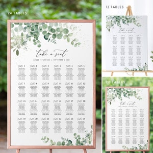 May include: A wedding seating chart with a eucalyptus and watercolor design. The chart is printed on white paper and has a gold frame. The text on the chart reads "Take a Seat" and includes the names of the bride and groom, the date of the wedding, and the table numbers. The chart is designed for 24 tables.