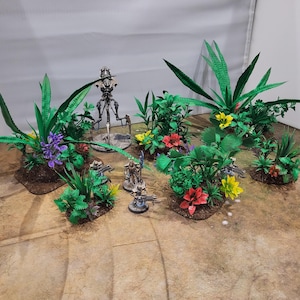 May include: A miniature terrain set with green foliage, colourful flowers, and small figurines. The set includes various plant arrangements with red, yellow, and purple flowers, and several small figurines. Suitable for tabletop gaming.