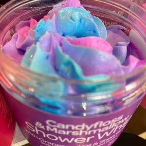 May include: A purple jar with a blue and pink swirl of whipped shower gel. The label reads "Candyfloss & Marshmallow Shower" with "Grapeseed Oil & Shea Butter Soft & Creamy Whipped Soap" in smaller text. The jar also has a vegan and cruelty-free logo.