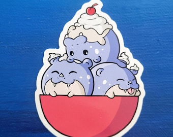 May include: Three cartoon purple and blue creatures with googly eyes and smiling faces are sitting in a red bowl. The creature on top has a white swirl on its head and a red cherry on top.