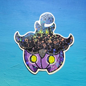 May include: A holographic sticker of a purple and black Pokemon with yellow eyes. The Pokemon is surrounded by a pattern of silver stars.