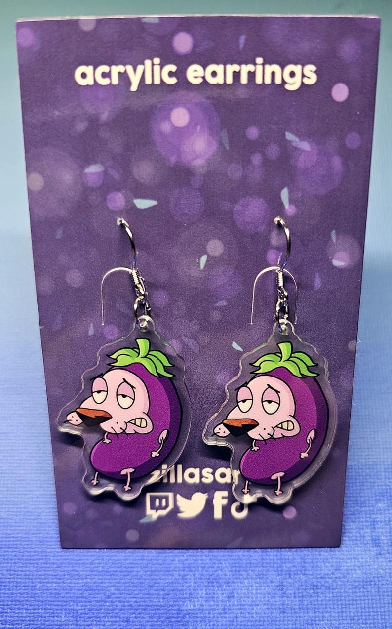 May include: Acrylic earrings featuring a cartoon eggplant character with a worried expression. The earrings are purple with green accents and silver hooks. The text "acrylic earrings" is at the top.