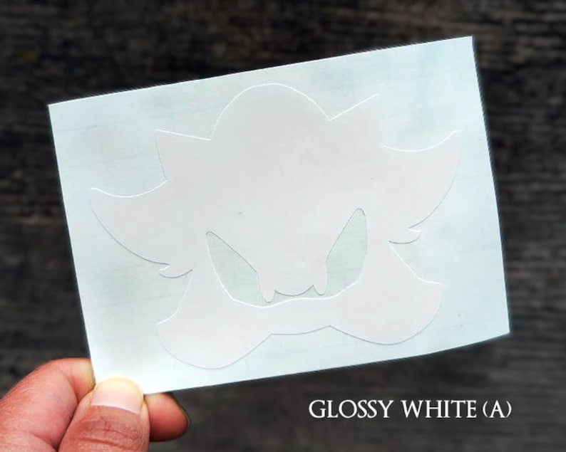 May include: White vinyl sticker with a silhouette of a cartoon character with a menacing expression. The character has a large head with sharp teeth and a pointed nose. The sticker is on a white background.
