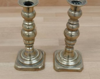 Può includere: Un paio di portacandele in metallo dorato con un design decorativo a perline. I portacandele hanno una base quadrata.