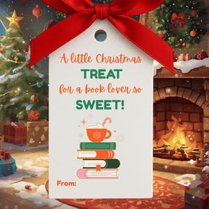 May include: A white gift tag with a red bow, featuring the text "A little Christmas TREAT for a book lover so SWEET!". The tag includes a stack of books and a cup of cocoa. The tag is designed for a Christmas gift.