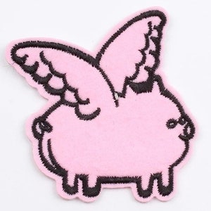 Puede incluir: Un parche rosa con un cerdo de dibujos animados con detalles bordados en negro y alas. El parche mide aproximadamente 15,2 x 17,8 cm. El cerdo tiene patas pequeñas y una cola rizada, con contornos negros.