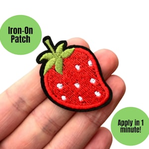 May include: A red strawberry iron-on patch with white seeds and a green stem. The patch has a black border. Text on the image says "Iron-On Patch" and "Apply in 1 minute!"