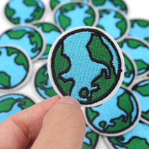 May include: Embroidered patches featuring a blue and green Earth design with a black outline and white border. The patches are round and have a detailed depiction of the continents and oceans. The patches are ideal for decorating clothing or accessories.