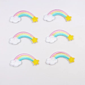 May include: Six embroidered rainbow patches. Each patch features a rainbow with pastel colors, a white cloud, and a yellow star. The patches are arranged on a white background.