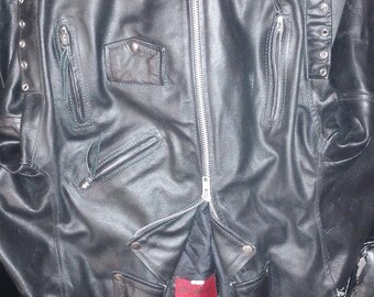 May include: Black leather motorcycle jacket with multiple pockets and a zipper closure. The jacket has a red label with the text "Genuine Leather" on the inside.