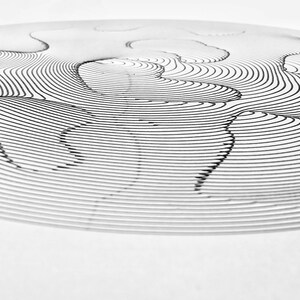 Op de afbeelding: Een abstracte tekening in zwart-wit van concentrische cirkels en golvende lijnen die een 3D-effect cre&euml;ren.