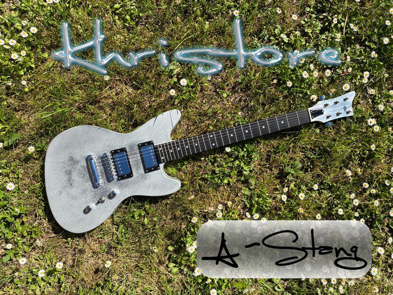 May include: A silver electric guitar with black and blue accents, resting on a bed of green grass and small white flowers. The word "Khristore" is written in a light blue, 3D font above the guitar. The text "A-Stong" is written below the guitar.