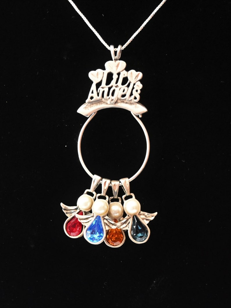 May include: Silver necklace with a charm that says "Life's Angels" and four angel charms with different coloured crystals.