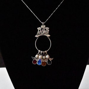 May include: Silver necklace with a pendant that says "My Angels" with a circle and five angel charms with coloured stones.