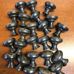 May include: A collection of dark gray cabinet knobs with a rounded top and a decorative pattern. The knobs are made of metal and have a classic design, suitable for furniture restoration or new builds.