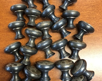 May include: A collection of dark gray cabinet knobs with a rounded top and a decorative pattern. The knobs are made of metal and have a classic design, suitable for furniture restoration or new builds.