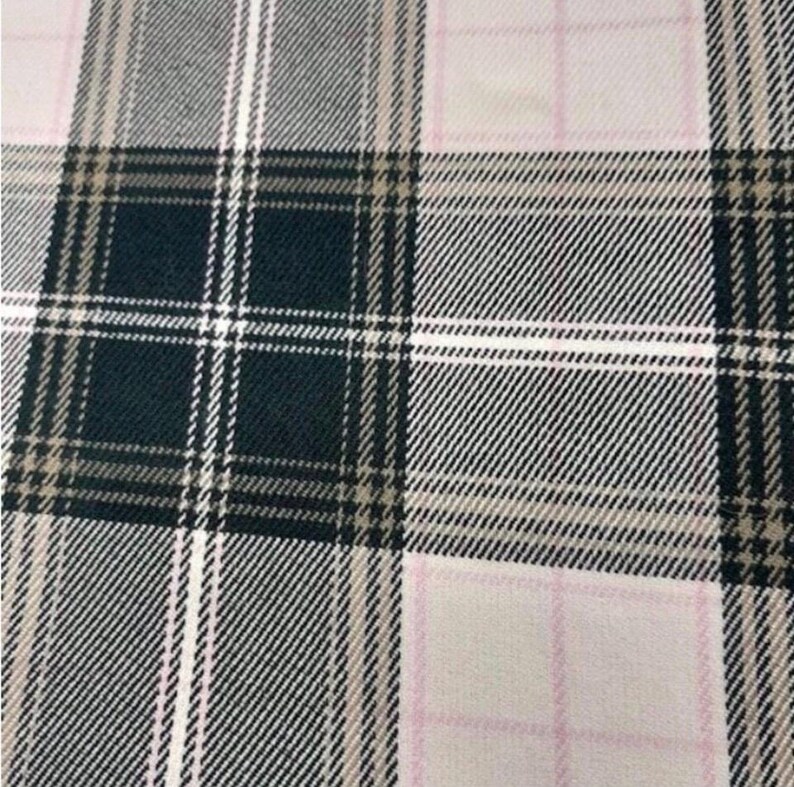 May include: Close-up of a fabric with a plaid pattern. The design features a grid of intersecting lines in shades of black, white, gray, tan, and pink. The fabric has a woven texture, suggesting it could be used for clothing or home decor.