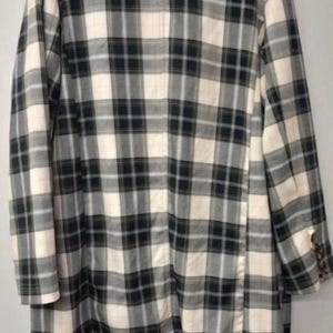 May include: A long, plaid blazer in a neutral color palette. The jacket features a classic black and white checkered pattern with a cream-colored background. The blazer has long sleeves and a buttoned cuff detail.