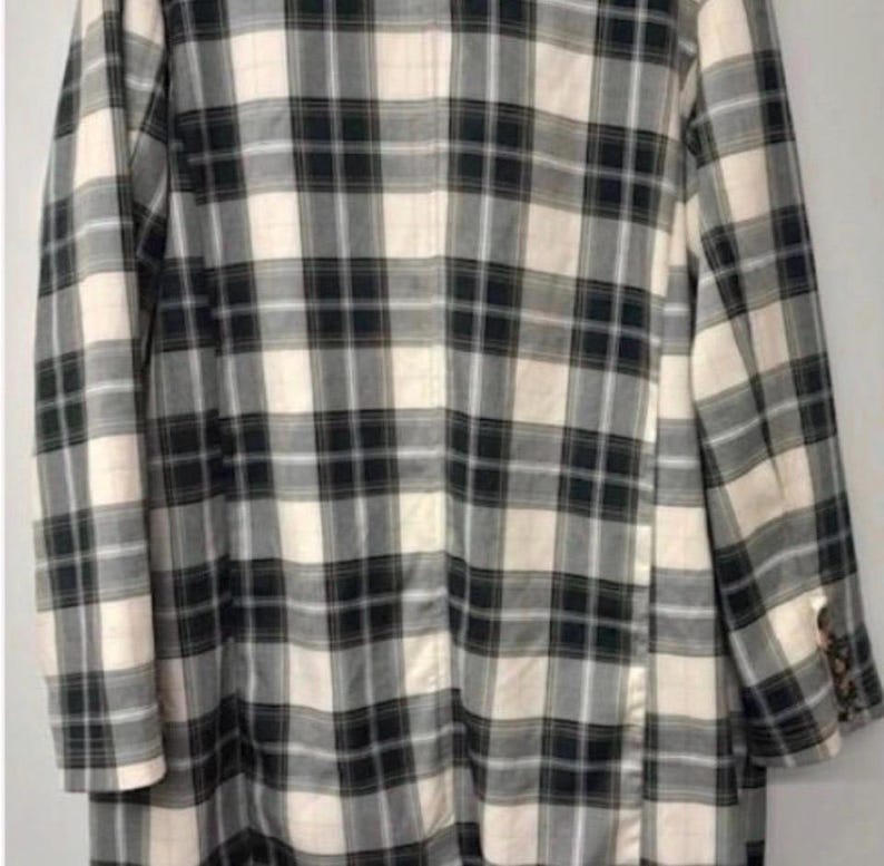 May include: A long, plaid blazer in a neutral color palette. The jacket features a classic black and white checkered pattern with a cream-colored background. The blazer has long sleeves and a buttoned cuff detail.