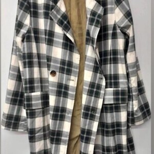 May include: A long, plaid coat in a black, white, and green pattern. The coat has a notched collar, two front pockets, and a single-button closure. The interior lining is a tan color.