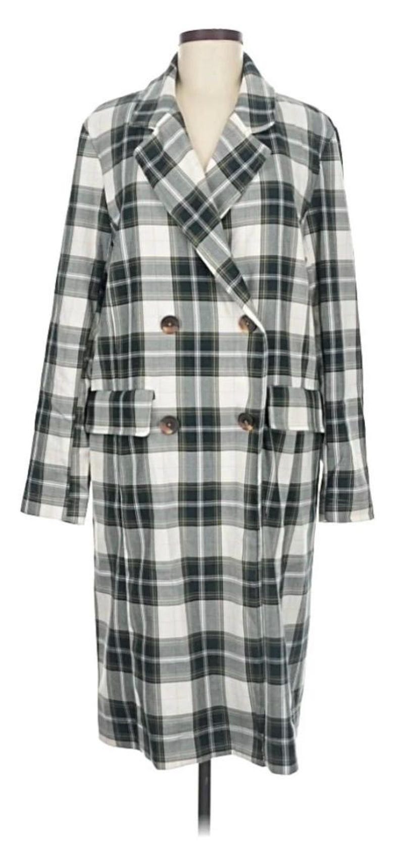 May include: A long, double-breasted plaid coat in a green, white, and black pattern. The coat has two rows of buttons, two front pockets, and a notched lapel. The coat is displayed on a mannequin.