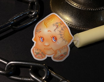 May include: A sticker of a cartoon baby with a snake tattoo and other tattoos on its arms. The baby has blonde hair and blue eyes. The sticker is on a dark background.