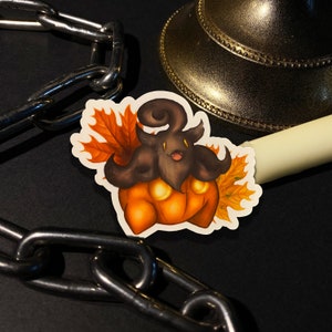May include: A sticker featuring a brown and orange pumpkin-shaped character with a black face and large, curled horns. The character is surrounded by orange and yellow fall leaves.