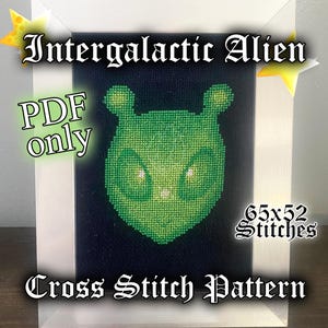 May include: A cross stitch pattern featuring a green alien with large eyes. The pattern is 65 stitches wide by 52 stitches tall. The text "Intergalactic Alien PDF only Cross Stitch Pattern" is displayed on the image.
