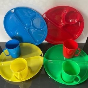 May include: Four divided plastic plates in blue, red, yellow, and green with four matching cups in the same colors.