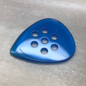 May include: A bright blue guitar pick with seven circular holes.