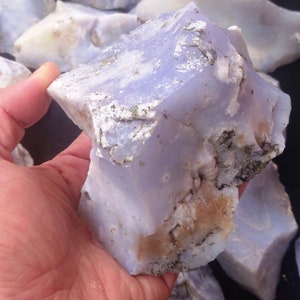 May include: A large, rough piece of blue lace agate with white and brown markings. The agate is translucent and has a milky blue color.