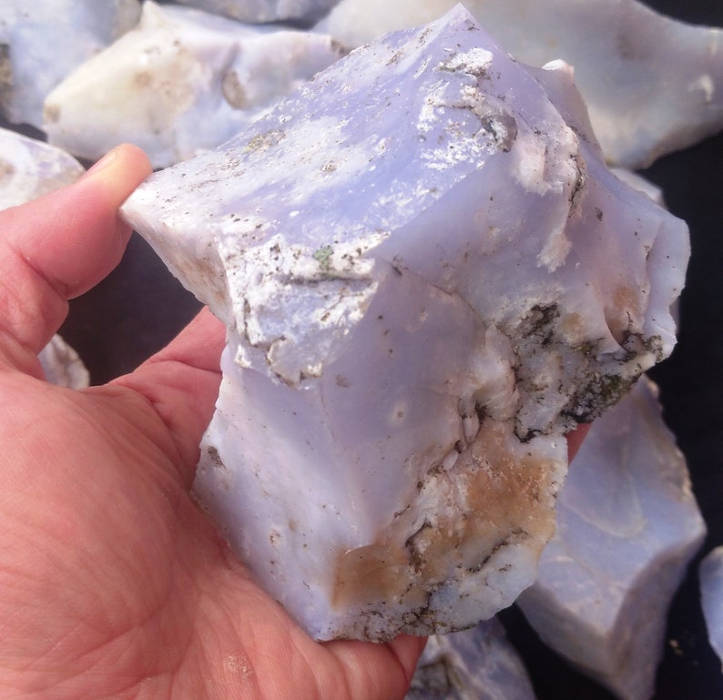 May include: A large, rough piece of blue lace agate with white and brown markings. The agate is translucent and has a milky blue color.