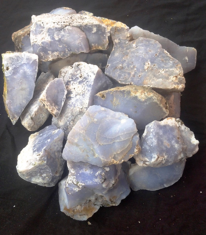 May include: A collection of rough, light blue and white agate stones. The stones are various sizes and shapes, with some showing a banded pattern.