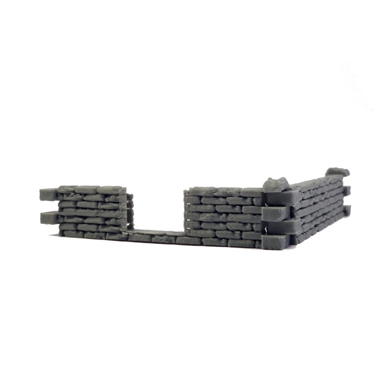 Puede incluir: Una secci&oacute;n de pared gris en miniatura construida con bloques rectangulares apilados. La estructura presenta un dise&ntilde;o en forma de L con un hueco central, similar a una abertura, y tiene una superficie texturizada que imita la mamposter&iacute;a.