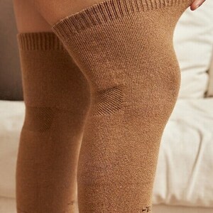 May include: Brown knee-high leg warmers. The warmers are made of a ribbed knit fabric and have a reinforced area over the knee. The cuffs are ribbed and the leg warmers are pulled up on the legs.