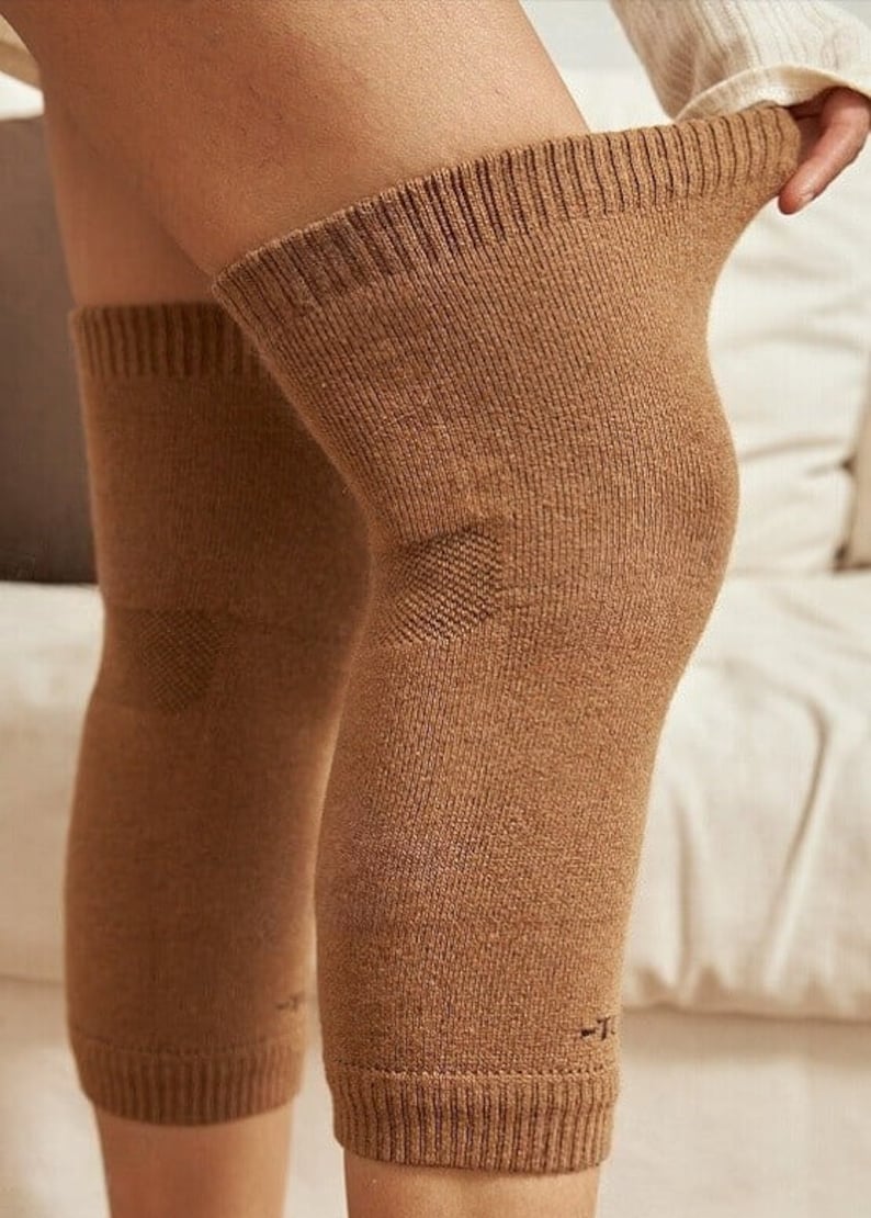 May include: Brown knee-high leg warmers. The warmers are made of a ribbed knit fabric and have a reinforced area over the knee. The cuffs are ribbed and the leg warmers are pulled up on the legs.