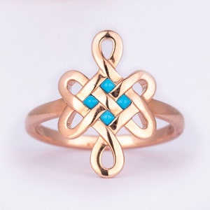 Puede incluir: Un anillo de oro rosa con un intrincado diseño de nudo con cuatro piedras preciosas de color azul turquesa. El anillo tiene un acabado pulido y una apariencia delicada y elegante, adecuado para el uso diario o ocasiones especiales.