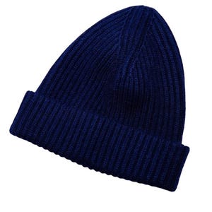 May include: A navy blue ribbed knit beanie hat. The hat has a folded brim and a close-fitting design. The hat is made of a soft, warm material, perfect for cold weather. This winter hat is a stylish accessory.