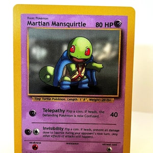 Puede incluir: Una carta de intercambio para el Pokémon Martian Mansquirtle. La carta es morada y presenta una ilustración de un Pokémon verde parecido a una tortuga que lleva una capa azul. La carta tiene un borde blanco y un texto que dice "Pokémon básico Martian Mansquirtle 80 PS".