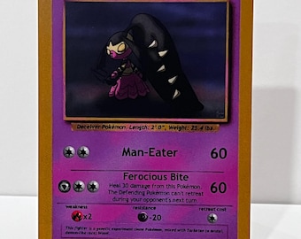 May include: A purple trading card featuring the character Mawileena with 100 HP. The card displays the attacks Man-Eater and Ferocious Bite, with text stating Deceiver Pokémon, Length: 2' 0", Weight: 25.4 lbs. The card has a gold border.