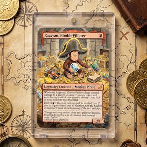 Op de afbeelding: Een Magic: The Gathering-kaart met Ragavan, Nimble Pilferer, een Monkey Pirate. De kaart zit in een beschermhoes, omringd door gouden munten, een kompas en een kaart. Een boek getiteld "The Curious Pilferer's Guide" is ook zichtbaar.