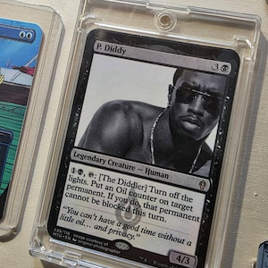 Op de afbeelding: Een Magic: The Gathering-kaart met P. Diddy in zwart-wit, in een doorzichtige plastic houder. De kaarttekst bevat "Legendary Creature - Human" en een citaat: "Je kunt geen leuke tijd hebben zonder een beetje olie... en privacy."